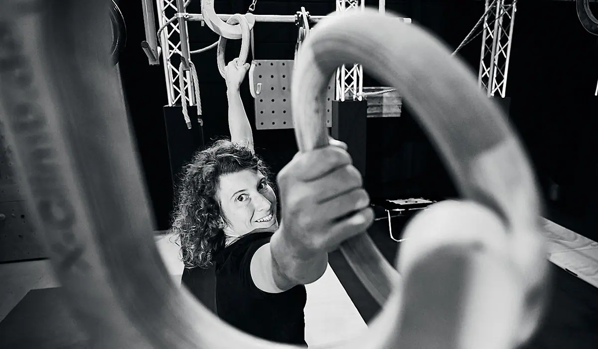 Frau hält sich in einer Kletterhalle an einem Ring fest