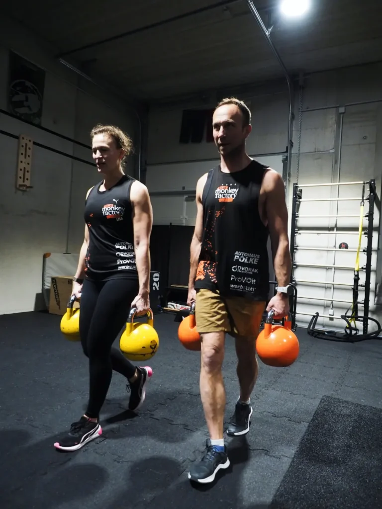 Zwei Personen trainieren Farmers carry kettlebell