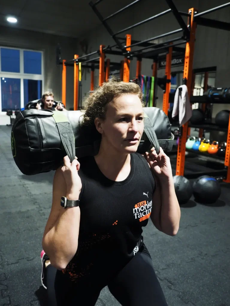 Frau trainiert Sandbag Lunges in der Monkey Factory