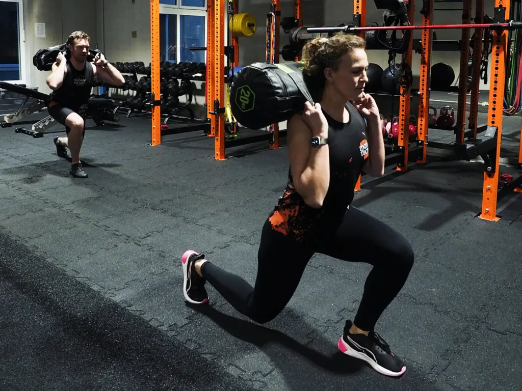 Frau macht im Fitnessstudio einen Sandbag walking lunges